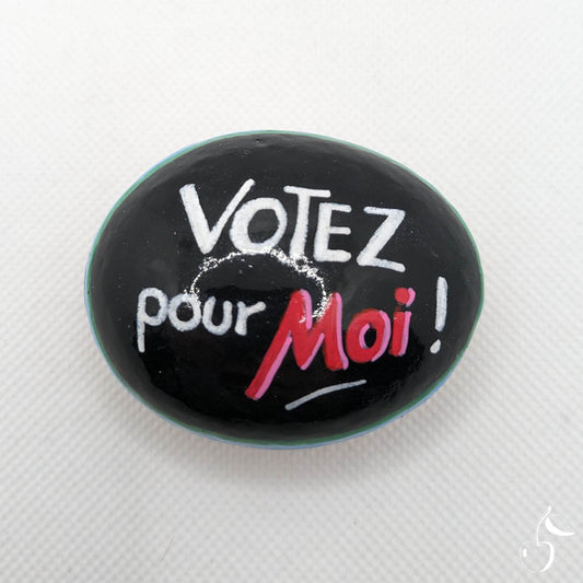 Galet noir avec écriture blanche et rouge "Votez pour moi !"