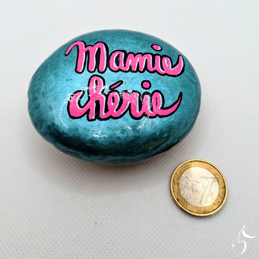 Galet peint en turquoise métallisé avec écrit en rose "Mamie chérie"