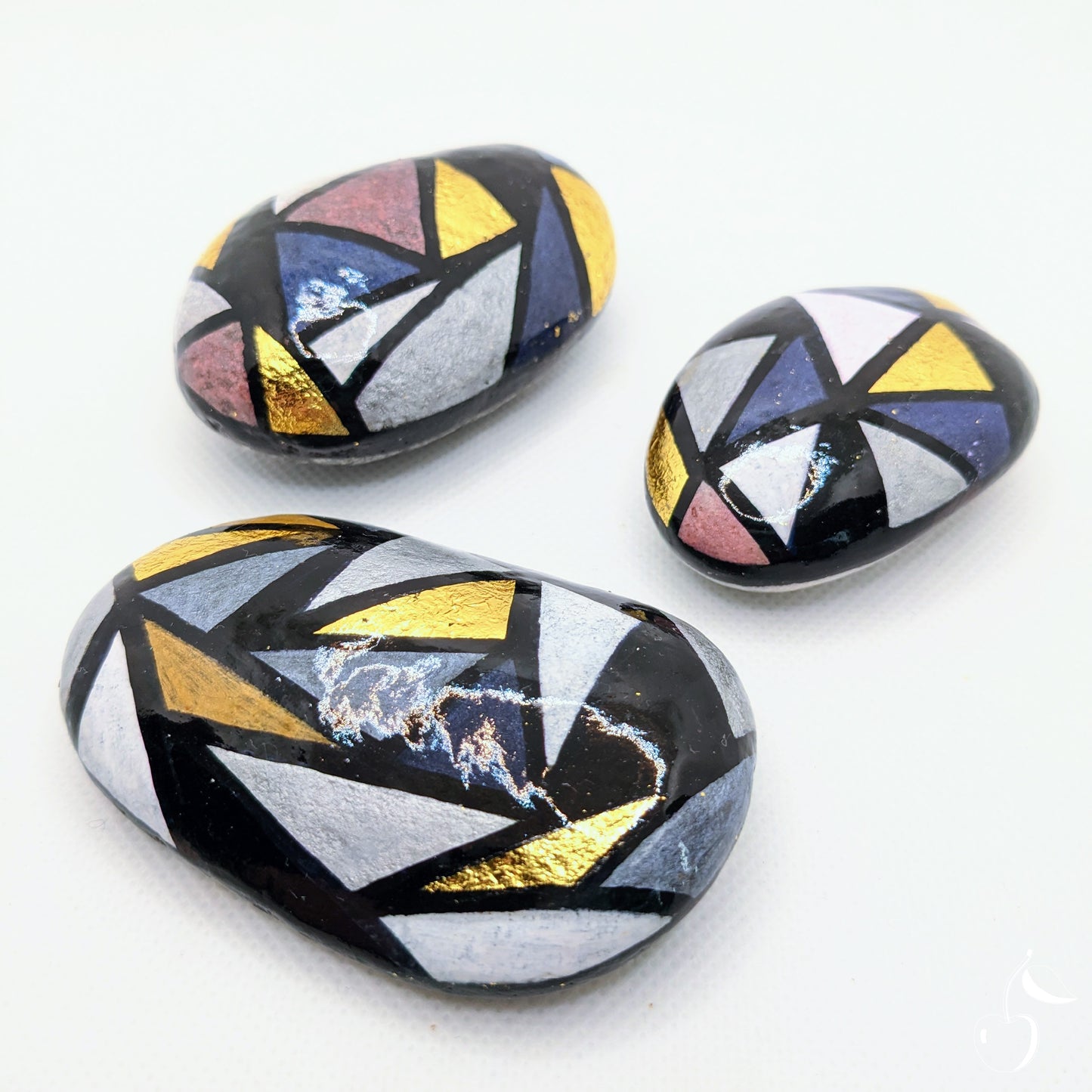 Galets peint avec des triangles grises, bleus et dorée