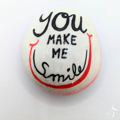 Galet blanc et rouge orné d'un grand sourire. Inscription "You make me smile" en son milieu.