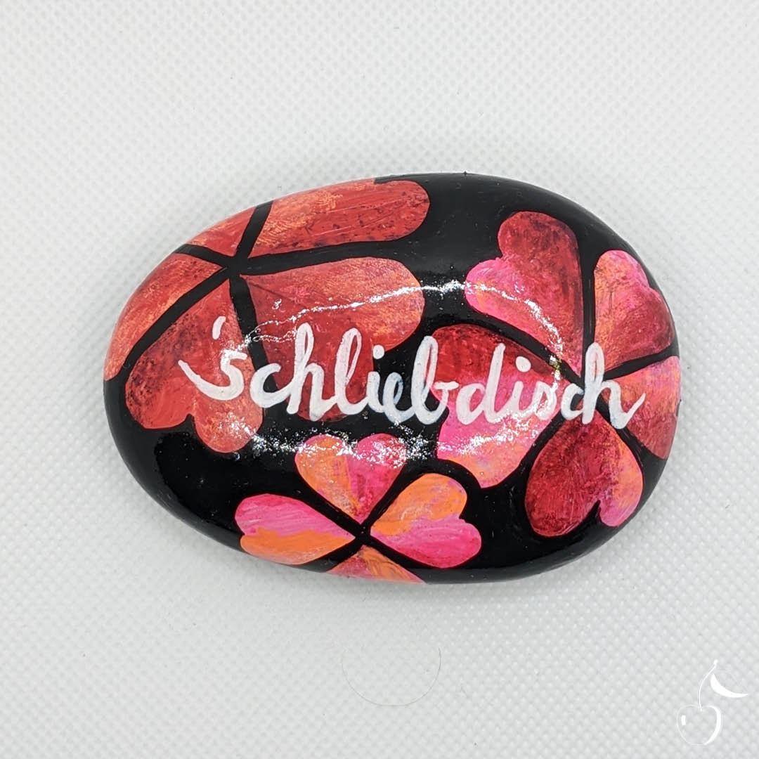 Galet avec coeurs roses et rouges sur fond noir avec écrit dans son centre en dialect colonais "Schliebdisch" Je t'aime